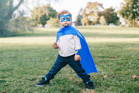 Cute adorable preschool Caucasian child playing superhero in blue costume. Boy kid wearing mask and...