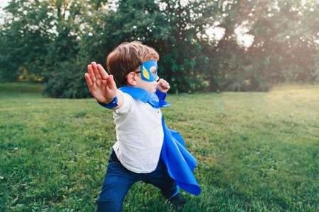 Cute adorable preschool Caucasian child playing superhero in blue costume. Boy kid wearing mask and...