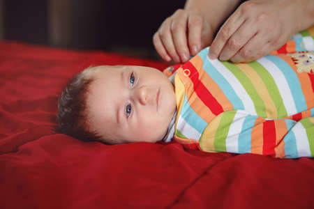 Parent caregiver changing diaper clothes for newborn baby boy girl laying on bed. Mother father...