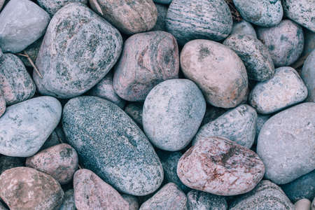Closeup of big huge large grey pink blue stones rocks pebbles lying on ground. Natural environmental background texture.Toned with modern hipster film filters.の写真素材