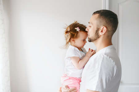 Caucasian father talking speaking with toddler baby girl. Male man parent holding embracing child....