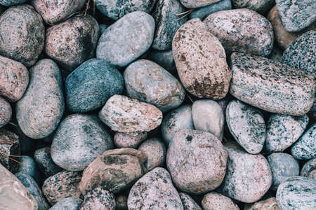Closeup of big huge large grey pink blue stones rocks pebbles lying on ground. Natural environmental background texture. Toned with modern hipster film filters.の写真素材