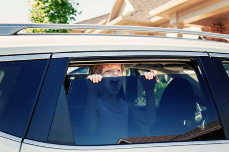 Preschooler little Caucasian girl left alone in car during hot sunny day. Child crying screaming...