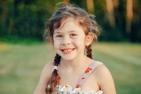 Closeup portrait of funny cute adorable smiling white Caucasian preschool girl with pigtails looking...