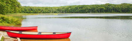 Beautiful landscape summer scene at Canadian Ontario Kettles lake in Midland area. Canada forest park nature with red kayaks canoe boats by water. Web banner header for website.の写真素材
