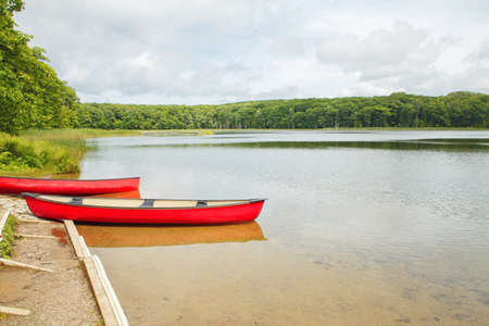 Beautiful landscape summer scene at Canadian Ontario Kettles lake in Midland area. Canada forest park nature with red kayaks canoe boats by water.の写真素材