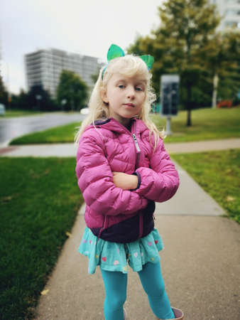 Portrait of cute adorable preschool funny Caucasian blonde girl wearing cat ears headband on her head. Little child kid playing posing outdoor in street.の写真素材
