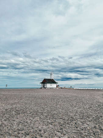 Beautiful landscape scenic view on Ontario lake in Canada. Overcast cloudy day with blue sky and clouds. Serene scene on desert beach with house booth cabin of lifeguards.の写真素材
