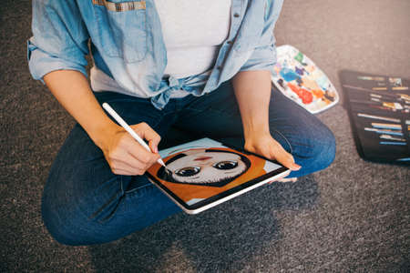 Lifestyle creative hobby and freelance artistic work job concept. Caucasian woman artist illustrator painting drawing on touch pad digital tablet with stylus. Process of creating illustration.の写真素材