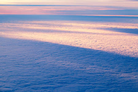Aerial view from airplane of bright colorful pink red yellow orange sun beams in clouds on light...