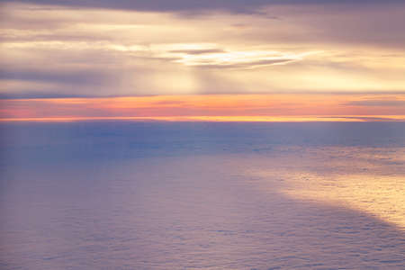 Aerial view from airplane of bright colorful pink red yellow orange sun beams in clouds on light...
