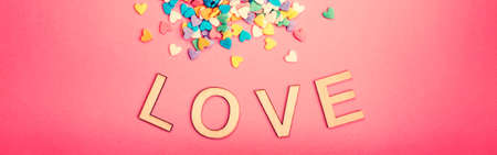 Happy Valentine Day. Beautiful card with colorful hearts candies on pink background. February holiday. Wooden words letters saying love. Web banner header for website.の写真素材