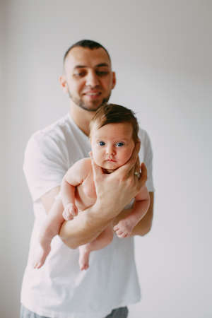 Happy Caucasian father holding newborn baby. Male bearded man parent rocking child daughter son on...