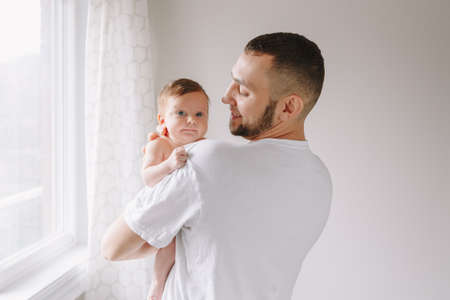 Happy Caucasian father holding newborn baby. Male bearded man parent rocking child daughter son on...