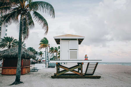 Lonely sad child girl sitting at lifeguard house on beach. Upset cute kid alone at sea ocean shore....