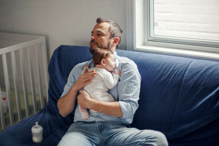 Middle age Caucasian father with sleeping newborn baby girl. Parent holding rocking child daughter...