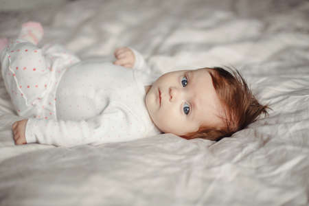 Closeup portrait of cute Caucasian newborn baby. Adorable funny child infant with blue grey eyes and...