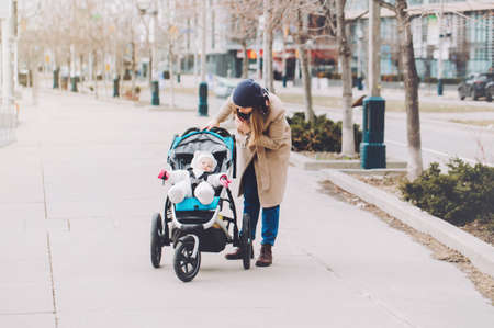 Happy young Caucasian mother walking with baby daughter outdoor in Toronto. Family two people...