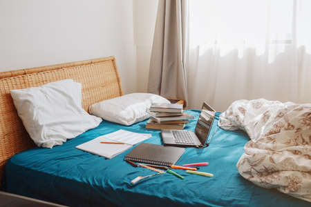 Home interior in bedroom with laptop and books for distant remote self education. Virtual class lesson on video online Internet during self isolation. Modern school study at quarantine.の写真素材