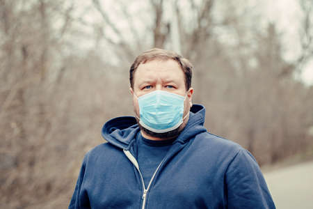 Caucasian young middle age man wearing sanitary face mask outdoor. Person protecting from dangerous...