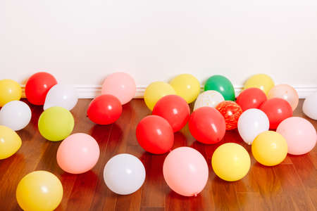 Group of many colorful air balloons lying on floor in studio apartment. Decoration interior for birthday holiday celebration. Festive background with copyspace. の写真素材