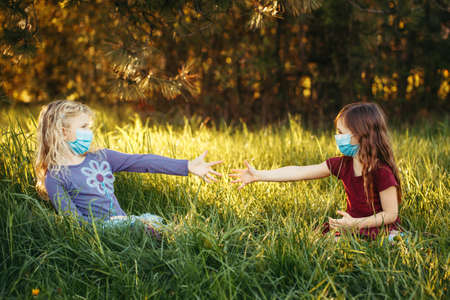 Cute girls friends in sanitary masks on faces. Preschool children kids wearing protective mask ....