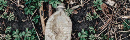 Old aged plastic bottle garbage trash litter on ground in green grass. Ecological environmental world nature problem concept. Protection and saving of nature. Banner header for website.の写真素材