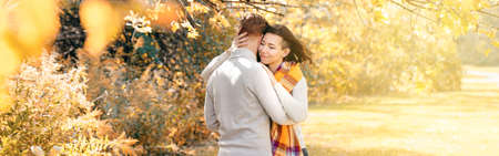 Beautiful couple man woman in love. Boyfriend and girlfriend hugging outdoor in park on autumn fall day. Concept of togetherness and happiness. Banner header for website.の写真素材
