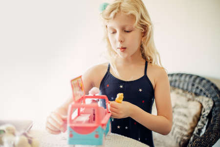 Cute little girl playing toy car bus with dolls. Active little child kid playing alone on a...