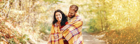Beautiful couple man woman in love. Boyfriend and girlfriend wrapped in yellow blanket hugging...
