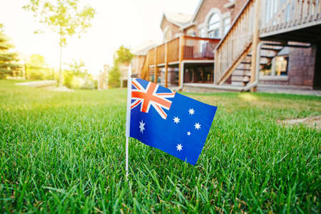 Australian flag standing on green grass in front of house. Australia day national holiday...
