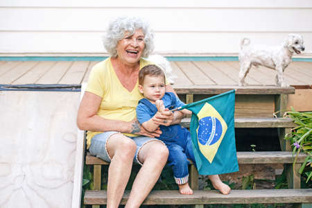 Proud citizens celebrating Independence Day of Brazil. Happy old woman with grandson baby holding...