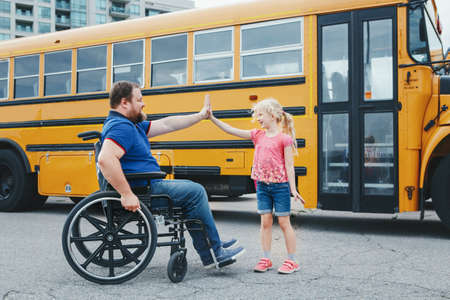 Encourage and support from family members. Disabled Caucasian father on wheelchair with daughter by...