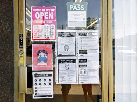 Toronto, Ontario, Canada - August 15, 2020: Warning notice on store shop door to wear protection face mask when entering. Precaution against coronavirus covid-19 spread. New normal rules.のeditorial素材