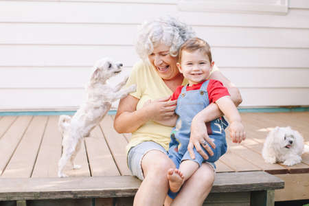 Grandmother sitting with grandson boy on porch at home backyard. Bonding of relatives and generation...