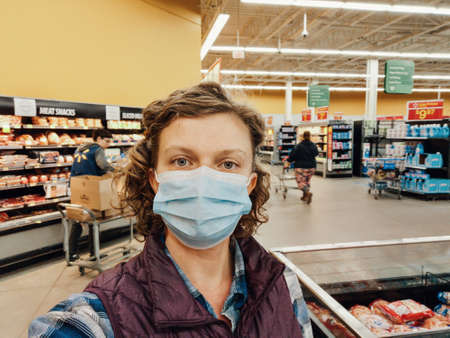 Toronto, Ontario, Canada - May 17, 2020: Woman customer in protective face mask shopping at grocery store. Safety measures against coronavirus covid-19 virus spread. New normal.のeditorial素材