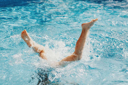 Funny child diving in swimming pool on home backyard. Kid child enjoying having fun in water. Summer...