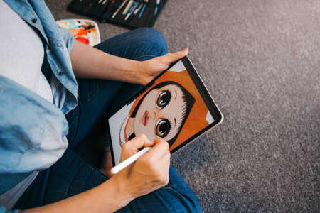 Creative hobby and freelance artistic work job. Caucasian woman artist illustrator painting drawing on touch pad digital tablet with stylus. Process of creating illustration. Unique profession.の写真素材