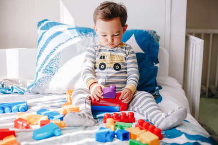 Cute baby toddler playing building with learning toy stacking blocks at home. Early age education. Kids hand brain and fine motor skills development. Logic activity for preschoolers.の写真素材