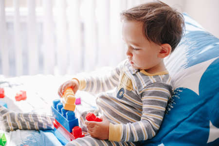 Cute baby toddler playing building with learning toy stacking blocks at home. Early age education....