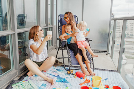 Young mothers spending time together with children babies on balcony at home.の写真素材