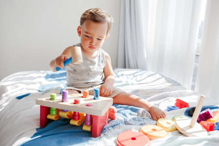 Cute baby toddler playing with learning multicolor toy pounding bench at home. Count learning. ...
