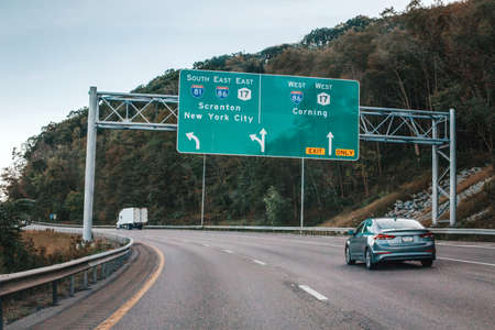 Cars on highway in American USA city country. Road to New York city. Green blue street signs to NY city. Empty road highway on summer day outdoors. Street road signs.の写真素材
