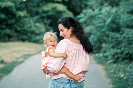 Mothers Day holiday. Young smiling Caucasian mother holding carrying girl toddler daughter. Mom...