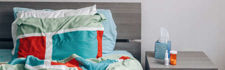 Cold season flue, virus illness. Pills, paper tissue, nasal spray, thermometer on table by bed in bedroom. Medicine and health care concept. Web banner or header.の写真素材