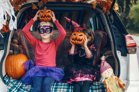 Trick or trunk. Children siblings sisters celebrating Halloween in trunk of car. Friends kids girls preparing for October holiday outdoor. Social distance,  safe alternative celebration.の写真素材