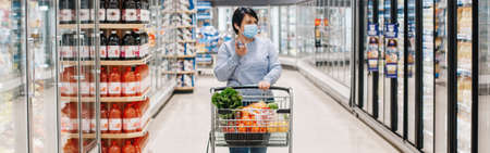 Middle age woman shopping in a grocery store supermarket and talking on audio chat phone. New social media chat app. Speaker in live stream on smartphone. Web banner header.の写真素材