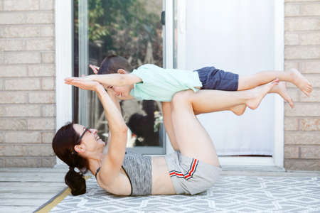Family sport activity. Caucasian mother with toddler son doing distant remote online fitness workout...