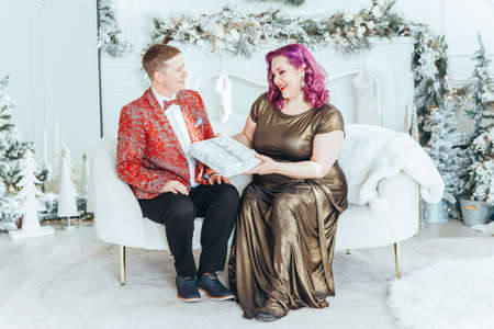LGBTQ lesbian couple celebrating Christmas New Year winter holiday. Gay female with butch partner giving gift boxes with presents to each other on Christmas Eve.の写真素材