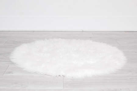 White round fluffy rug carpet lying on floor by white wall at home. Background mockup for designs and backdrop.の写真素材